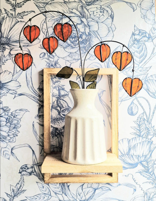 Chinese Lantern Plant Stem: “Orange stained glass Chinese lantern stems with green leaves displayed in a white vase.”